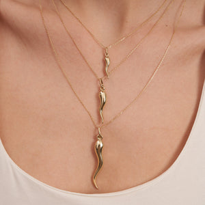 A 14K Real Gold Italian Horn Chili Pepper Pendant Necklace gently dangles from a delicate chain, offering Cornicello protection against a pristine white backdrop.