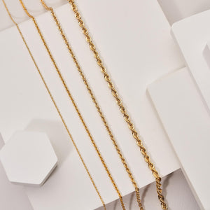 The 14K Solid Gold Rope Chain for Women & Men is beautifully showcased against a white background. With its intricate, twisted design, this chain offers a textured appearance. Its genuine gold composition forms a gentle curve, highlighting its smooth and polished finish.