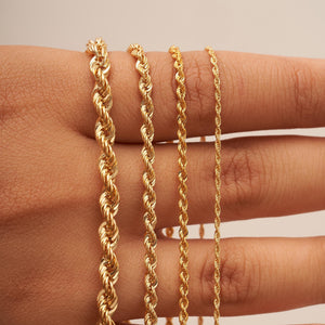 The 14K Solid Gold Rope Chain for Women & Men is beautifully showcased against a white background. With its intricate, twisted design, this chain offers a textured appearance. Its genuine gold composition forms a gentle curve, highlighting its smooth and polished finish.