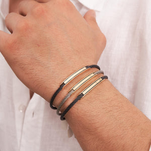 Introducing the 14K Solid Gold Nameplate ID Bracelet for Men, showcasing a sleek design with a twisted black band and a polished gold bar at the center. It features a 14K solid gold nameplate clasp, blending modern elegance that's perfect for those who appreciate fine men's jewelry.