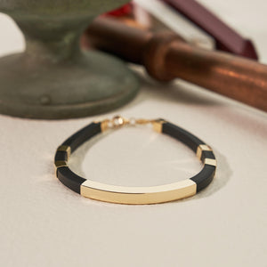 A modern and elegant bracelet designed for men, showcasing square tube nameplate ID with segments of black rubber complemented by shiny engraved gold bars, and secured with a 14K solid gold clasp. Perfect for custom engraving.