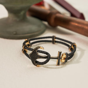 Introducing the 14K Real Solid Gold & Braided Leather Anchor Black Cord Bracelet for Men: A chic bracelet that combines a braided black leather strap with luxurious gold details, including a prominent studded anchor centerpiece. It also features a secure clasp and offers customizable chain sizing for an ideal fit.