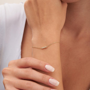 The Diamond Bar Bracelet in 14K Solid Gold for Women is an exquisite piece, featuring a delicate chain with a small rectangular bar embellished with tiny gemstones. It includes an adjustable closure with several loops to ensure a perfect fit, highlighting the elegance and allure of genuine gold.