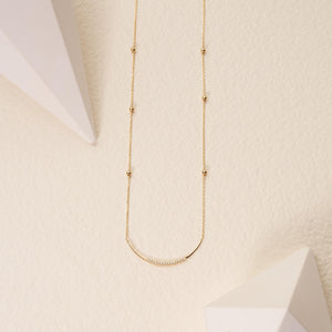 Introducing the Curved Natural Diamond Bar Necklace in 14K Solid Gold, a refined piece featuring a delicate genuine gold chain accented with evenly spaced beads. This elegant necklace exudes a minimalistic charm and includes a curved bar pendant adorned with small natural diamonds, epitomizing sustainable jewelry design.