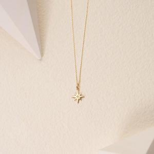 This eco-friendly jewelry item is the Diamond North Star Necklace in 14K Gold for Women. It includes a fine gold chain with a star-shaped pendant, which features a polished surface and is adorned with a natural diamond at its center, offering an elegant sparkle.