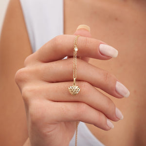 The Real Diamond 3D Puffy Heart Necklace in 14K Gold showcases a heart-shaped pendant on a chain. Crafted from solid gold, the pendant features an open lattice design, offering a delicate and elegant look. The genuine gold's luxury is beautifully highlighted against a white background.