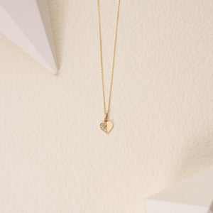 The 14K Solid Gold Tiny Diamond Heart Necklace boasts a heart-shaped pendant that is artistically divided; one side gleams with polished gold, while the other dazzles with an array of small diamonds, creating a stunning sparkle. This exquisite piece exemplifies sustainable handcrafting, featuring a chain that is both delicate and finely crafted.