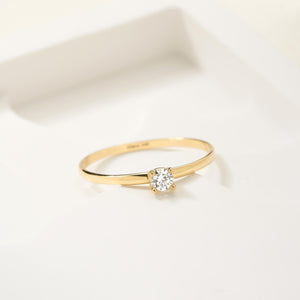 Presenting the 14K Solid Gold Genuine 3 mm Diamond Solitaire Ring, an exquisite engagement piece featuring a single 0.11 Ct. natural diamond set gracefully in a prong setting. The band is slender and refined, enhancing the brilliance of the gemstone against its plain white backdrop, which highlights the simplicity and beauty of this authentic gold ring.