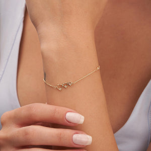 Introducing the Triple Diamond Heart Bracelet in 14K Solid Gold for Women, a delicate gold bracelet featuring a chain crafted from 14K solid gold. It is adorned with heart-shaped links and highlighted by natural diamond accents, complete with a small clasp for secure fastening.