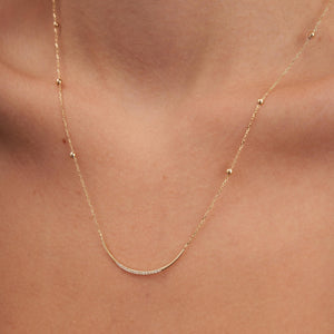 Introducing the Curved Natural Diamond Bar Necklace in 14K Solid Gold, a refined piece featuring a delicate genuine gold chain accented with evenly spaced beads. This elegant necklace exudes a minimalistic charm and includes a curved bar pendant adorned with small natural diamonds, epitomizing sustainable jewelry design.