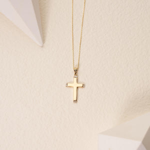 A 14K Solid Gold Diamond Cross Necklace featuring a genuine gold chain and a cross pendant. The elegantly designed cross has a smooth finish with small natural diamonds adorning each of its four ends, while the finely linked, delicate chain exemplifies sustainable jewelry craftsmanship.