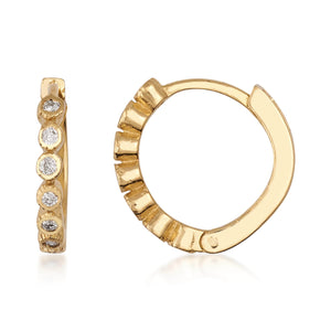 The Genuine Diamond Hoop Earrings in 14K Solid Gold include one earring lying flat and the other standing upright. These elegant earrings are crafted with genuine gold and adorned with a row of small, round white diamonds along the outer edge, giving them a shimmering appearance.