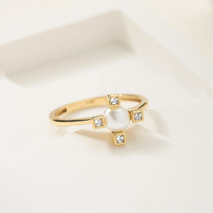 This dainty engagement ring, named the 14K Solid Gold Pearl Diamond Ring, features a central pearl surrounded by four square diamonds on extended gold arms forming a striking cross shape.