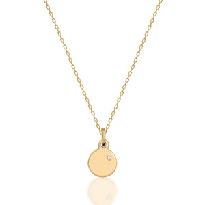 The 14K Solid Gold Round Disc Diamond Necklace showcases a smooth gold pendant with a subtle diamond accent on a delicate chain, artfully presented against a white background.