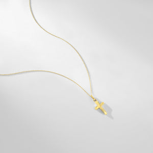 The 14K Gold Tiny Cross Necklace, featuring a small and simple solid yellow gold pendant, is elegantly showcased against a pristine white background. This hypoallergenic jewelry piece combines timeless style with comfort.