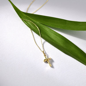 The 14K Gold Tiny Cross Necklace, featuring a small and simple solid yellow gold pendant, is elegantly showcased against a pristine white background. This hypoallergenic jewelry piece combines timeless style with comfort.