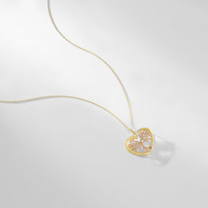 The Heart & Tree of Life Necklace features a heart-shaped pendant adorned with an intricate tree design, expertly crafted in 14K tri-tone gold. It is suspended from a delicate chain, showcasing the harmonious blend of rose and yellow gold tones against a simple white backdrop.