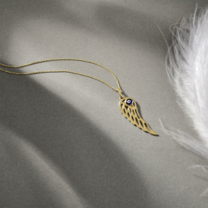 The 14K Gold Angel Wing Pendant Charm Necklace features a captivating angel wing pendant with an eye motif at its center, elegantly suspended from a delicate chain against a pristine white backdrop. This necklace is hypoallergenic and radiates elegance.