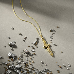 Introducing the 14K Solid Gold Sword Necklace, a stunning jewelry piece with a delicate chain and an elegant sword-shaped pendant. This hypoallergenic necklace features intricate designs adorned with subtle cubic zirconia embellishments. Its beauty is accentuated against a simple white background.