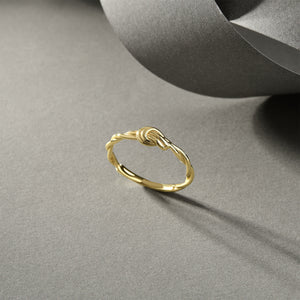 The 14k Solid Gold Knot Ring features a twisted band and is set against a white background, highlighting its simple and elegant design. Perfect as a minimalist stackable gold ring, it effortlessly captures timeless beauty.