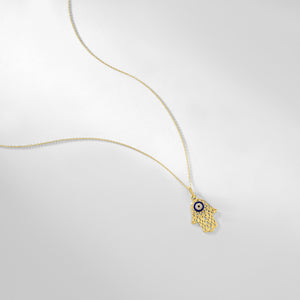 The 14K Gold Hamsa & Evil Eye Necklace features a mesmerizing blue and white evil eye design at its center, set within a stunning solid gold hamsa pendant.