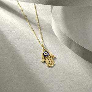 The 14K Gold Hamsa & Evil Eye Necklace features a mesmerizing blue and white evil eye design at its center, set within a stunning solid gold hamsa pendant.