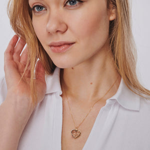 The Heart & Tree of Life Necklace features a heart-shaped pendant adorned with an intricate tree design, expertly crafted in 14K tri-tone gold. It is suspended from a delicate chain, showcasing the harmonious blend of rose and yellow gold tones against a simple white backdrop.