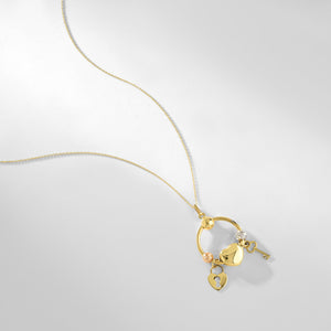 The 14K Solid Gold Heart Lock Key Necklace by RundaJewelryUs features a circular pendant adorned with three charms: a silver key, a gold heart, and a gold padlock with a keyhole. This pendant gracefully hangs from an elegant, delicate gold chain, capturing the timeless beauty of the lock and key design.