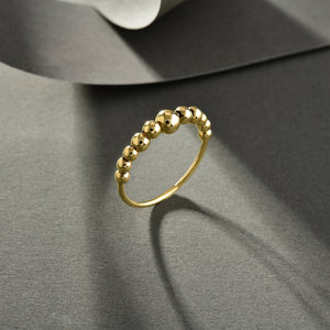 The 14k Gold Bubble Ring features a series of polished, spherical beads, resulting in a delicate and elegant design. This handcrafted piece boasts a smooth finish with a simple yet stylish look, beautifully highlighted against a plain white background to emphasize its genuine allure.