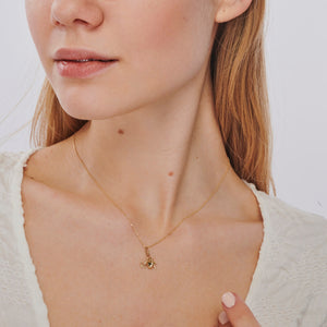 The Faith Hope Love Necklace is a 14K Gold Necklace adorned with a Cross Charm Pendant along with heart and anchor charms, representing faith, hope, and love. Each charm gracefully hangs from a delicate gold chain set against a pristine white background.