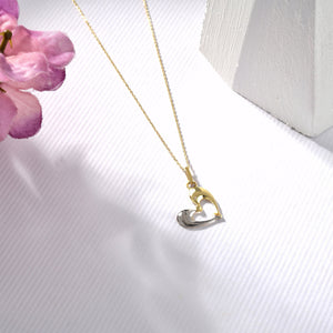 A delicate 14K solid gold necklace featuring a pendant shaped like a graceful dolphin, crafted in striking yellow-white gold and silver. The design is elegant and minimalistic, set against a white background.