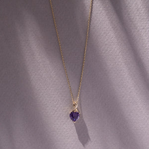 The 14K Solid Gold Amethyst Heart Pendant Necklace features a heart-shaped amethyst elegantly set in a sophisticated twist design, suspended from a delicate gold chain.