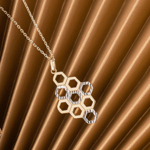 Experience the elegance of the 14K Solid Gold Honeycomb Necklace by RundaJewelryUs, featuring a geometric pendant with interconnected hexagonal shapes in both gold and silver tones. This exquisite piece perfectly captures a honeycomb pattern, beautifully blending nature's charm with modern design.