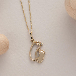 This exquisite piece, the 14K Solid Gold New Baby Feet Necklace by RundaJewelryUs, showcases a pendant in the shape of two baby footprints. It's an ideal choice for new moms, with one footprint featuring a small diamond. The pendant elegantly dangles from a delicate chain.