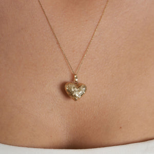 The 14K Gold 3D Puffy Heart Necklace, featuring a minimalist heart pendant with a woven texture, elegantly dangles on a delicate chain against a white background.