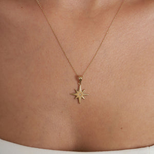 The 14K Gold North Star Pendant Necklace by RundaJewelryUs features a North Star pendant crafted from solid gold with eight symmetrical points and a small central gemstone, hanging elegantly from a delicate chain, making it an ideal graduation gift.