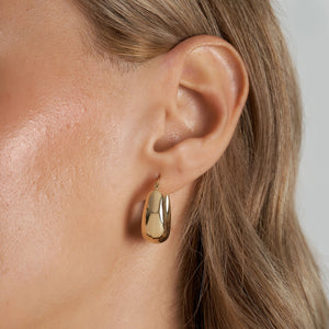 Introducing our 14K Real Gold Thick Hoop Earrings: These elegant earrings showcase a chunky design with a polished gold finish, offering a shiny surface. Crafted from 14k gold, they feature an oval shape with a secure clasp closure. The earrings are beautifully displayed against a plain white background.