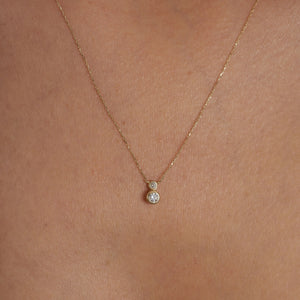 The 14K Gold Zirconia Necklace showcases two round diamond pendants on a delicate chain, arranged vertically with the larger pendant positioned below the smaller one. The white background enhances the necklace's elegance, making it an ideal piece of dainty gold jewelry for bridal occasions.