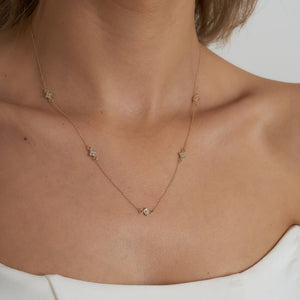 A refined 14K gold necklace adorned with evenly spaced, small flower-shaped diamond pendants along the chain, elegantly showcased on a white background.