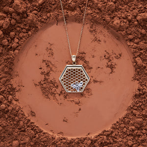 The 14K Gold Queen Bee Pendant Necklace by RundaJewelryUs features a stunning hexagonal honeycomb pendant, beautifully embellished with a delicate bee design, and gracefully suspended on a fine chain.