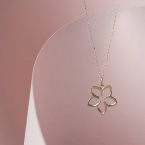 The 14K Gold Plumeria Necklace by RundaJewelryUs features a delicate pendant with a five-petal floral outline, crafted in authentic 14k gold.