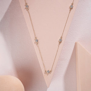 A refined 14K gold necklace adorned with evenly spaced, small flower-shaped diamond pendants along the chain, elegantly showcased on a white background.