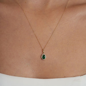 The 14K Gold Oval Emerald Necklace showcases a delicate oval pendant adorned with a prominent green emerald, surrounded by sparkling zirconia stones, making it an ideal choice for women who value elegance.