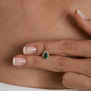 The 14K Gold Oval Emerald Necklace showcases a delicate oval pendant adorned with a prominent green emerald, surrounded by sparkling zirconia stones, making it an ideal choice for women who value elegance.