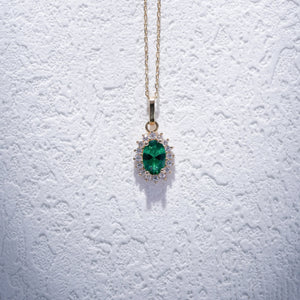 The 14K Gold Oval Emerald Necklace showcases a delicate oval pendant adorned with a prominent green emerald, surrounded by sparkling zirconia stones, making it an ideal choice for women who value elegance.