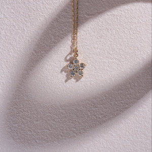 A 14K gold chain necklace from RundaJewelryUs, featuring a pendant shaped like a flower, crafted from six small round diamonds.