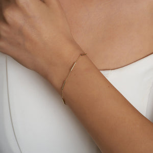 Introducing the 14K Gold Minimal Station Bracelet by RundaJewelryUs: a delicate design featuring a thin chain accented with small, evenly spaced tube-shaped beads in lustrous 14K gold. This elegant piece is securely fastened with a traditional lobster claw closure.