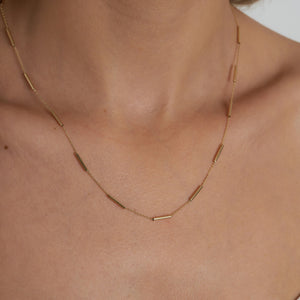 The 14K Gold Station Minimal Chain Necklace features small, evenly spaced bar links arranged in a circular shape against a plain white background, making it ideal for layering or wearing alone as a standout solid gold chain piece.