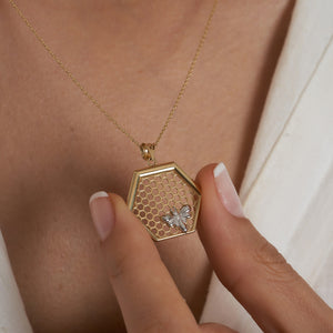 The 14K Gold Queen Bee Pendant Necklace by RundaJewelryUs features a stunning hexagonal honeycomb pendant, beautifully embellished with a delicate bee design, and gracefully suspended on a fine chain.