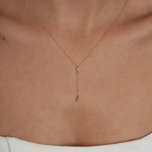 Introducing the 14K Gold Y Minimal Diamond Chain Necklace by RundaJewelryUs, a delicate piece showcasing two small round diamond pendants elegantly spaced along the chain. One pendant drapes lower for a sophisticated layered look against a plain white background.